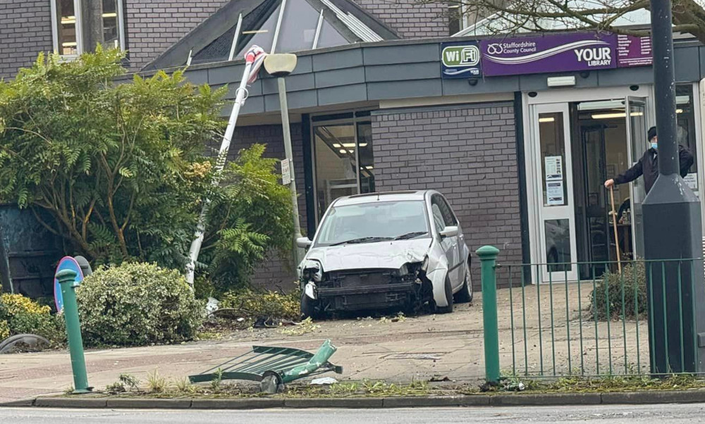 A mangled car alongside the flag pole, which has been knocked over and now rests against the roof of the Library.